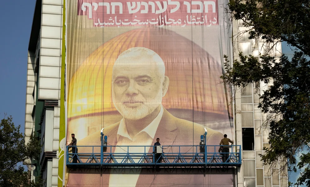 Iranian workers install a huge banner on a wall showing a portrait of Hamas leader Ismail Haniyeh and the Dome of Rock Mosque at the Al-Aqsa Mosque compound of Jerusalem with a sign which reads in Farsi and Hebrew: "Wait for severe punishment," at Felestin (Palestine) Sq. in Tehran, Iran, Wednesday, July 31, 2024. Haniyeh was assassinated in Tehran, Iran's paramilitary Revolutionary Guard said early Wednesday. (AP Photo/Vahid Salemi)