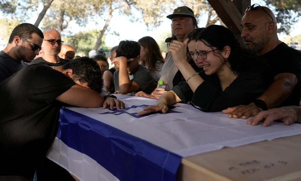 Family members mourn over the coffin of Yoram Metzger during his funeral at a cemetery of the kibbutz Nir Oz, southern Israel, Thursday, Aug. 22, 2024. Metzger's body was one the six bodies of hostages, taken in Hamas' Oct. 7 attack, recovered by Israel's military during an operation in the Gaza Strip. (AP Photo/Tsafrir Abayov)