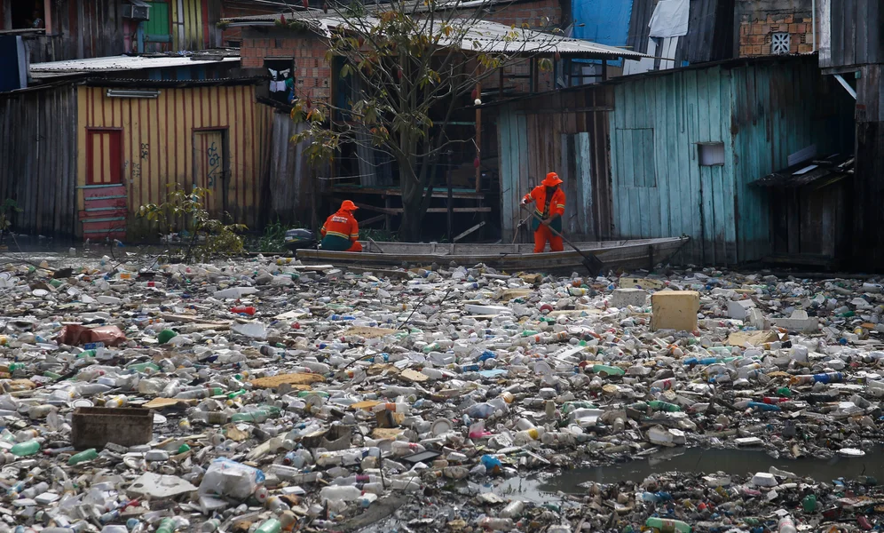 FILE - City workers remove garbage floating on the Negro River, which has a rising water level due to rain, in Manaus, Amazonas state, Brazil, June 6, 2022. (AP Photo/Edmar Barros, File)