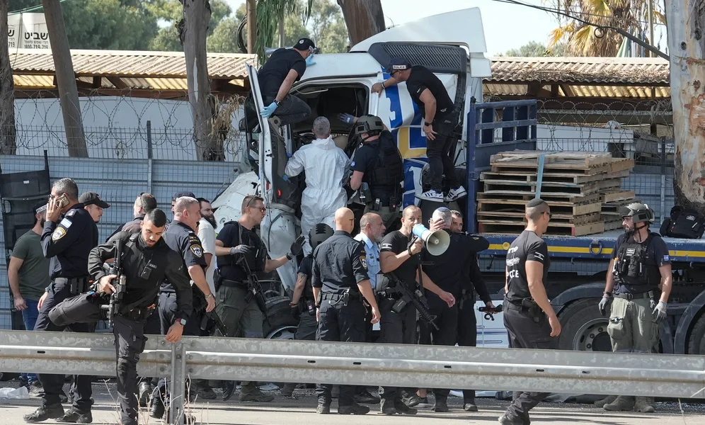 Israeli police climb on a truck that rammed into a bus stop near the headquarters of Israel's Mossad spy agency, wounding dozens of people, according to Israel's Magen David Adom rescue service in Tel Aviv, Israel, Sunday, Oct. 27, 2024. (AP Photo/Oded Balilty)