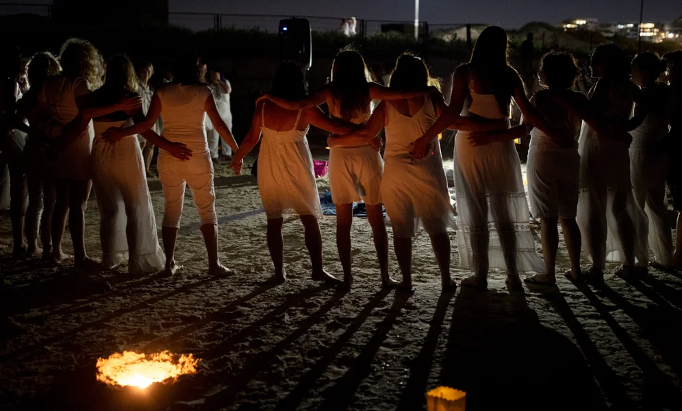 Women take part in a Tashlich ceremony, where they wrote down things they want to release before casting them into a fire, on the beach in Tel Aviv, Israel, Tuesday, Sept. 14, 2021. Tashlich, which means 'to cast away' in Hebrew, is the practice by which Jews go to a large flowing body of water and symbolically 'throw away' their sins by throwing a piece of bread, or similar food, into the water before the Jewish holiday of Yom Kippur, the holiest day in the Jewish year which starts at sundown Wednesday. (AP Photo/Maya Alleruzzo)