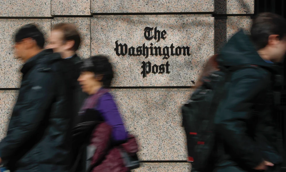 FILE - People walk by the One Franklin Square Building, home of The Washington Post newspaper, in downtown Washington, Feb. 21, 2019. New leaders of The Washington Post are being haunted by their past, with ethical questions raised about their actions as journalists in London that illustrate very different press traditions in the United States and England. (AP Photo/Pablo Martinez Monsivais, File)