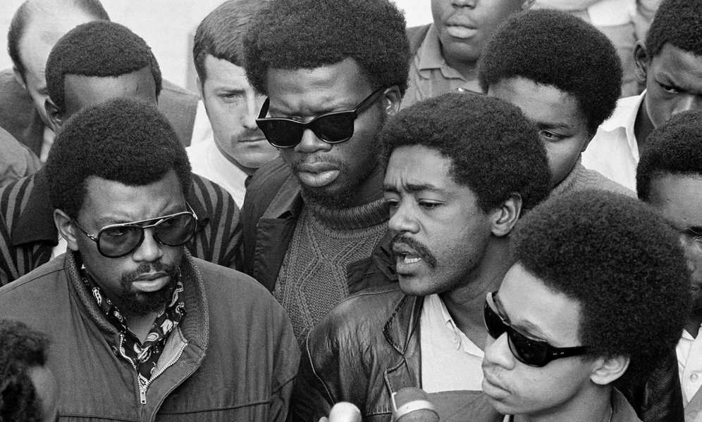 Bobby Seale, right, chairman of the Black Panther Party, is one of three speakers at a sidewalk news conference in Oakland, Ca., Nov. 21, 1968. The other speakers are Ben Stewart, left, head of the Black Students organization at San Francisco State, and George Murray, center dark glasses, suspended teacher at State. (AP Photo/Ernest K. Bennett)